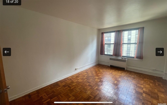 empty room featuring dark parquet floors and radiator