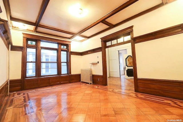 unfurnished room featuring beamed ceiling, radiator heating unit, and wood walls