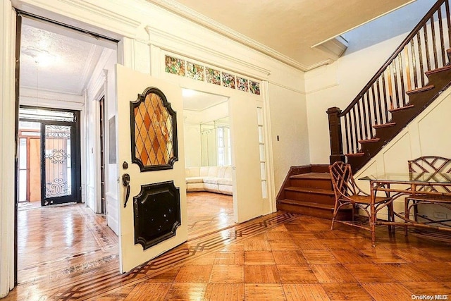 foyer featuring plenty of natural light, parquet flooring, and crown molding