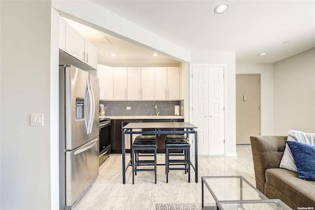 kitchen with white cabinetry, sink, stainless steel fridge with ice dispenser, black electric range oven, and decorative backsplash