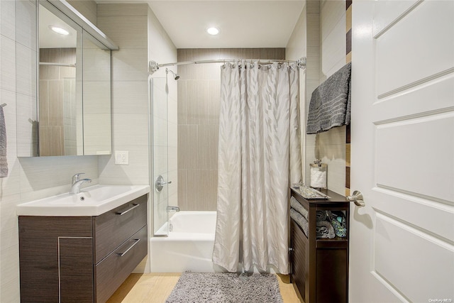 bathroom featuring shower / bath combo with shower curtain, vanity, and tile walls