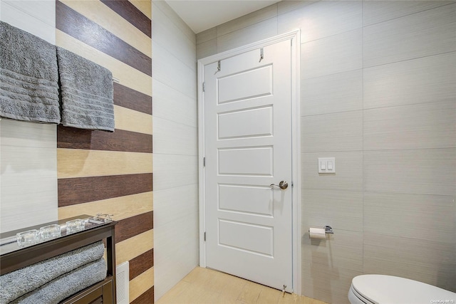 bathroom with toilet and tile walls