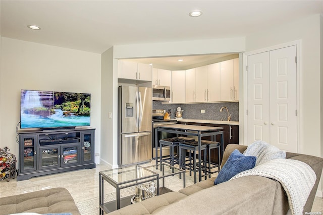 kitchen featuring tasteful backsplash, open floor plan, white cabinetry, appliances with stainless steel finishes, and light countertops