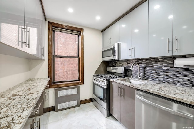 kitchen with sink, backsplash, light stone counters, and stainless steel appliances