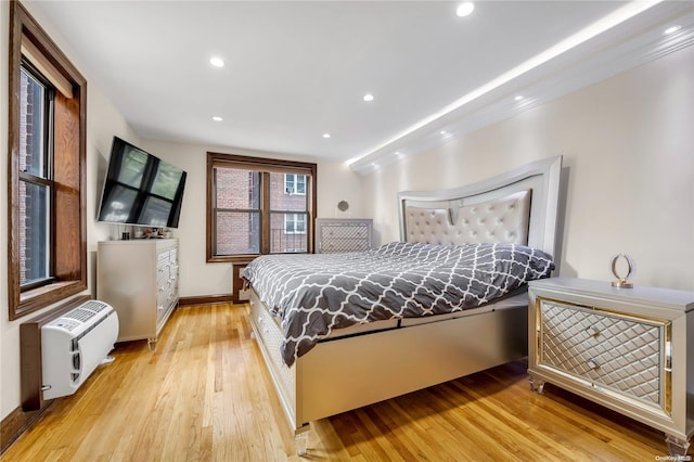 bedroom with heating unit and light hardwood / wood-style flooring