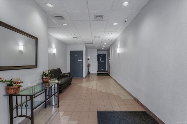 hall featuring tile patterned floors and a drop ceiling