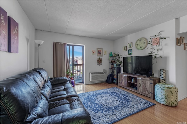 living room featuring wood-type flooring, a textured ceiling, and an AC wall unit