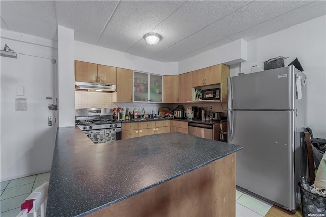 kitchen featuring sink, light tile patterned floors, tasteful backsplash, kitchen peninsula, and stainless steel appliances