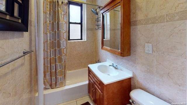 full bathroom with vanity, shower / bathtub combination with curtain, tile walls, tile patterned flooring, and toilet