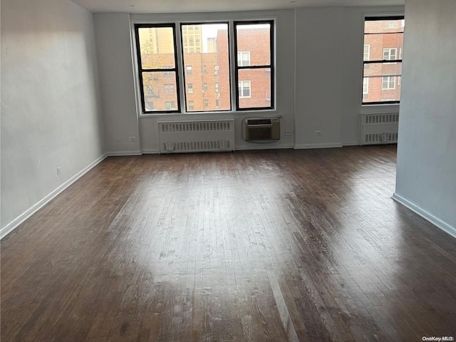 unfurnished room with dark wood finished floors, radiator, a wall mounted AC, and baseboards