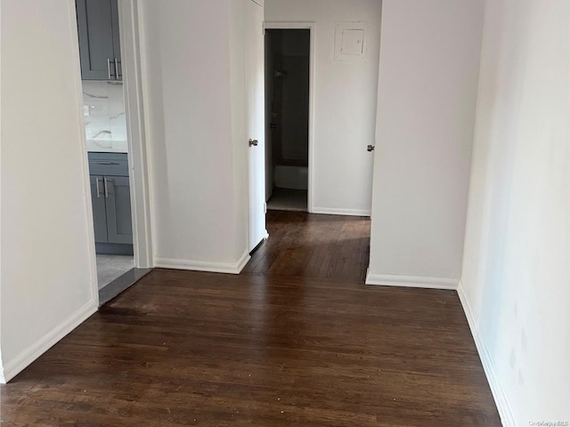 corridor featuring baseboards and wood finished floors