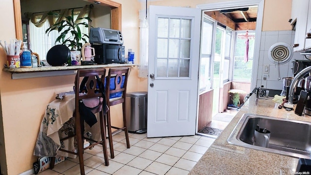 kitchen with light tile patterned floors, light stone counters, and sink