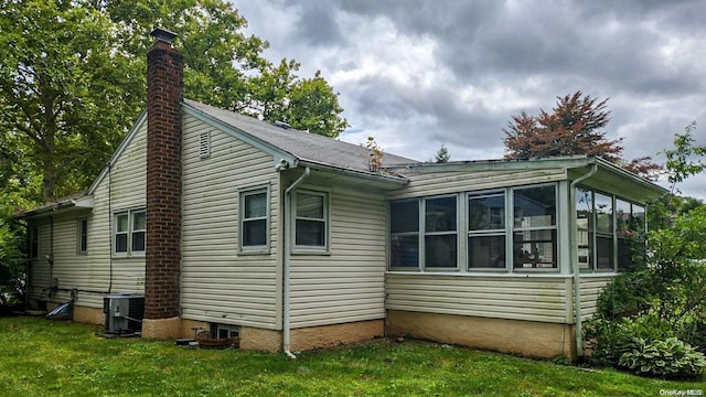 view of property exterior featuring a sunroom, central air condition unit, and a yard