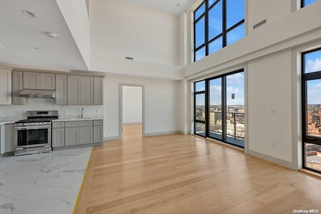 kitchen featuring gray cabinets, stainless steel gas range oven, and a healthy amount of sunlight