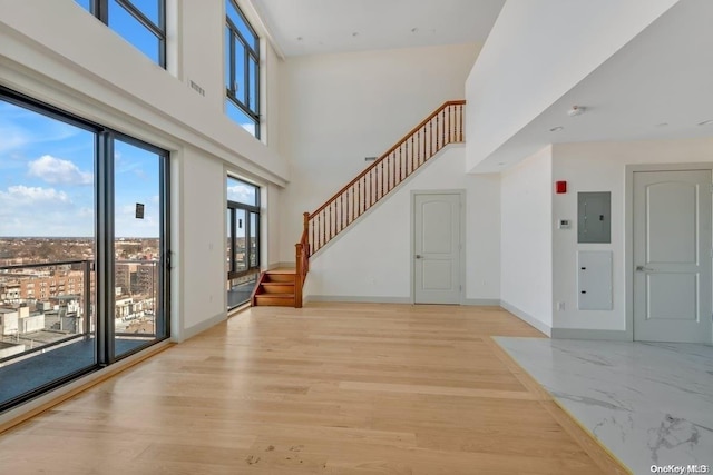 entrance foyer with electric panel, light hardwood / wood-style flooring, and a high ceiling