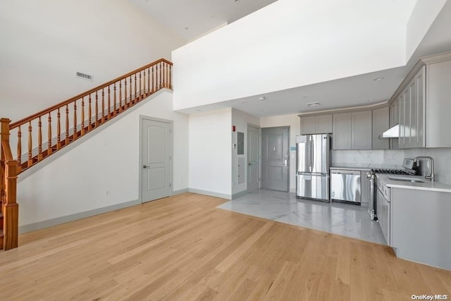 kitchen featuring gray cabinetry, ventilation hood, stainless steel appliances, and light hardwood / wood-style floors