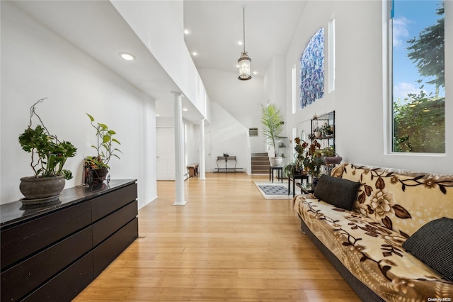 living room featuring a high ceiling, decorative columns, and light hardwood / wood-style floors