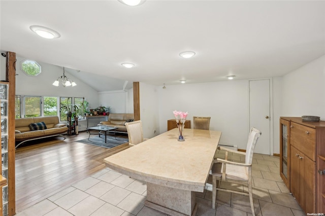 dining room with a notable chandelier, a baseboard heating unit, lofted ceiling, and light hardwood / wood-style flooring