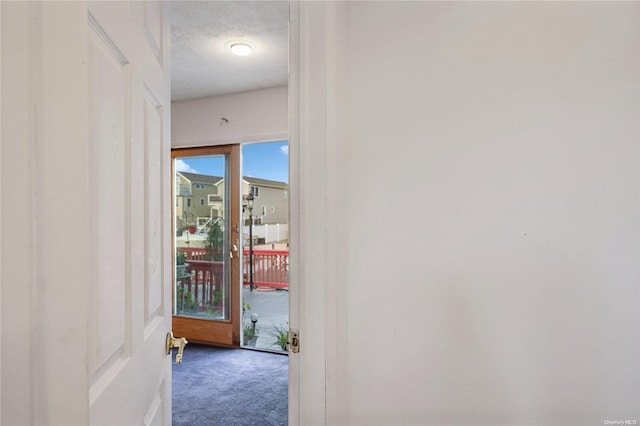 hall featuring a textured ceiling and carpet floors