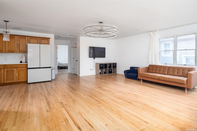 unfurnished living room featuring light hardwood / wood-style flooring and a notable chandelier