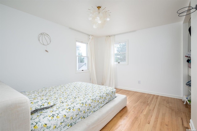 bedroom with hardwood / wood-style flooring and a notable chandelier