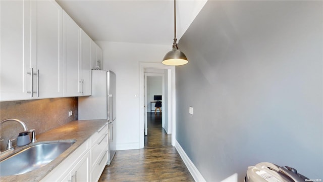 kitchen with pendant lighting, dark hardwood / wood-style flooring, white cabinetry, and sink