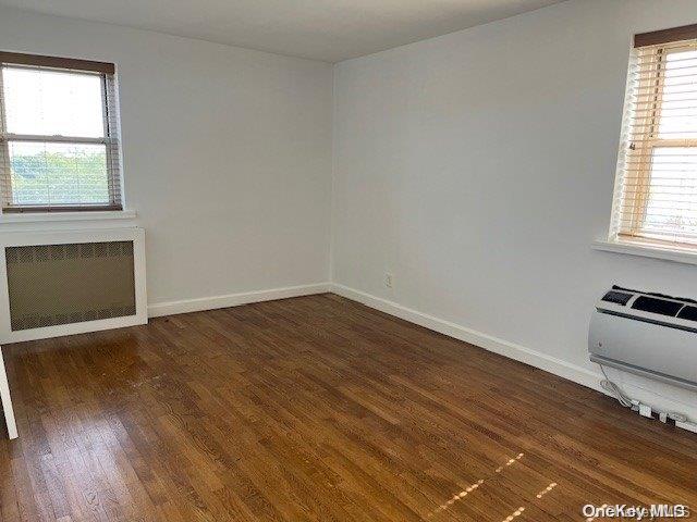 spare room with dark hardwood / wood-style flooring, radiator, and a wall mounted AC