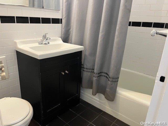 full bathroom with backsplash, tile patterned floors, shower / bath combo with shower curtain, tile walls, and toilet