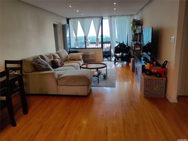 living room featuring light hardwood / wood-style flooring, a wall of windows, and an AC wall unit