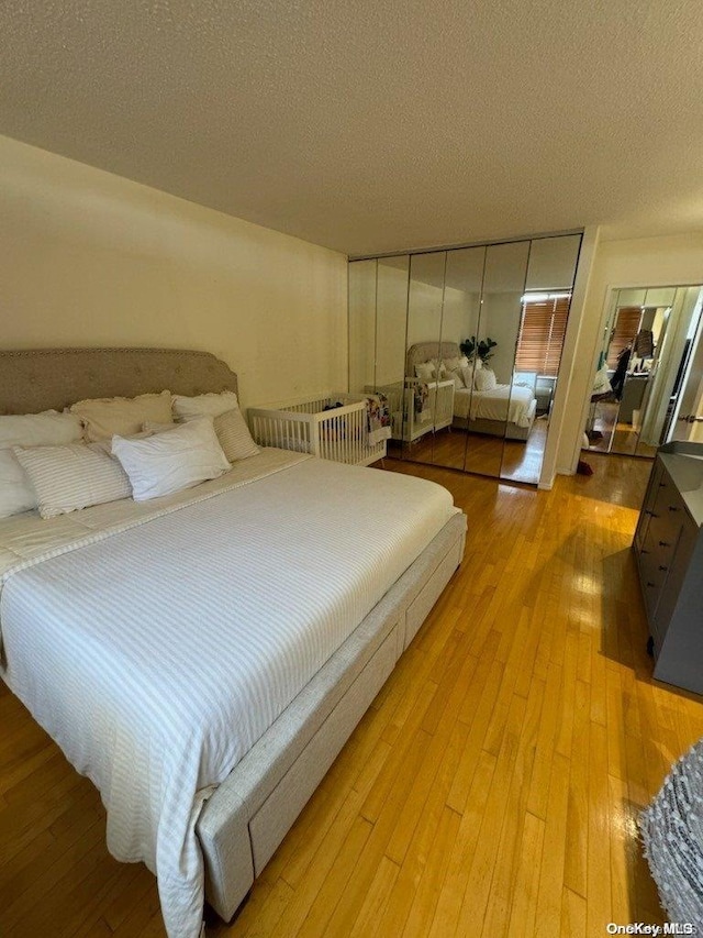 bedroom featuring light hardwood / wood-style floors, a textured ceiling, and a closet