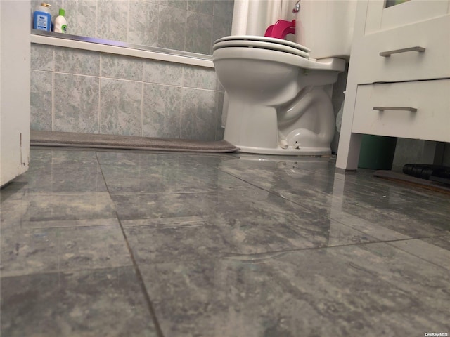 bathroom featuring tile walls and toilet