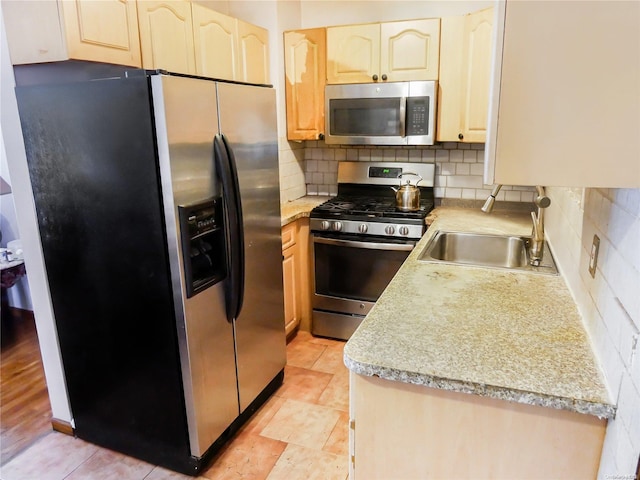 kitchen featuring light brown cabinets, sink, light wood-type flooring, tasteful backsplash, and stainless steel appliances