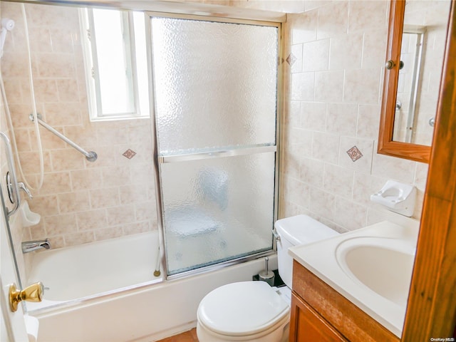 full bathroom with vanity, toilet, combined bath / shower with glass door, and tile walls