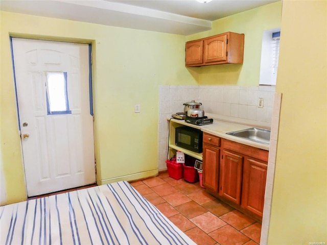 kitchen with backsplash, light tile patterned flooring, and sink