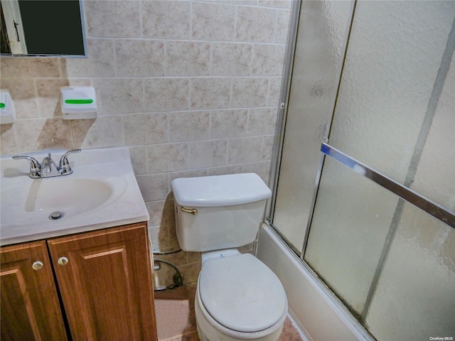 full bathroom with shower / bath combination with glass door, vanity, toilet, and tile walls