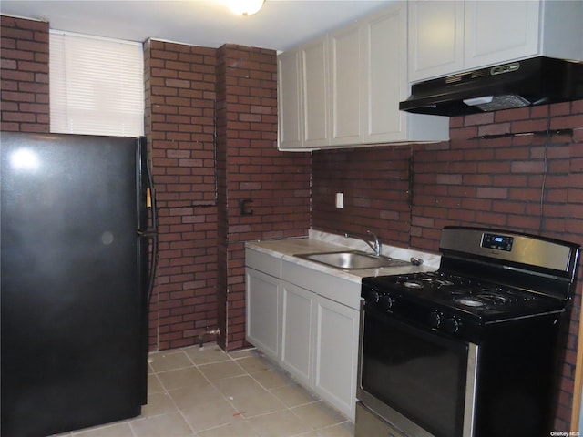 kitchen with stainless steel gas stove, sink, light tile patterned floors, black refrigerator, and white cabinets