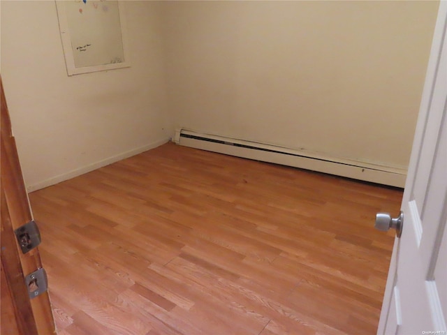 unfurnished room featuring light wood-type flooring and a baseboard heating unit