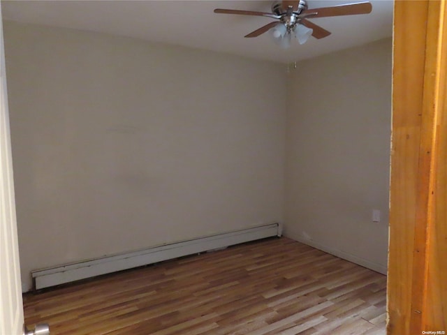 empty room featuring ceiling fan, wood-type flooring, and a baseboard heating unit