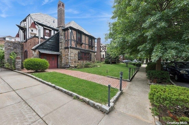 29-37 168th St, Flushing, NY 11358 - view of side of property featuring a yard, stone siding, a chimney, an attached garage, and driveway