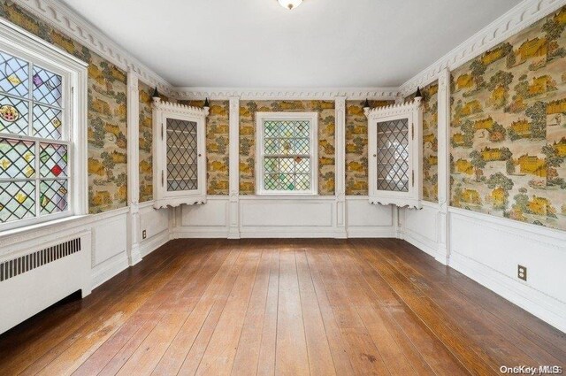 29-37 168th St, Flushing, NY 11358 - unfurnished sunroom featuring radiator heating unit, wood-type flooring, and wallpapered walls