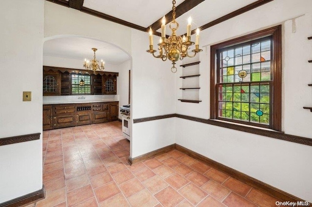 unfurnished dining area featuring a chandelier, beam ceiling, tile patterned floors, and ornamental molding