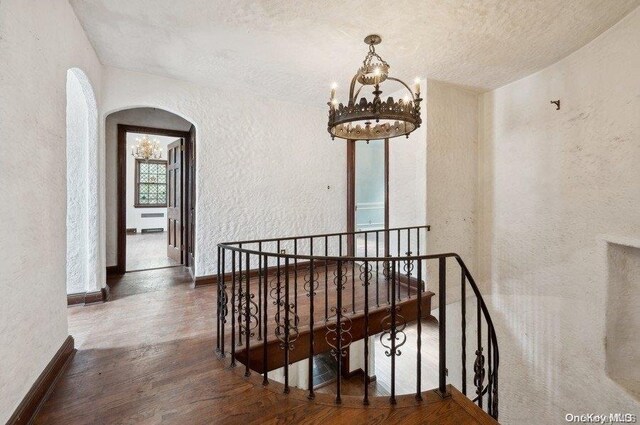 29-37 168th St, Flushing, NY 11358 - stairway featuring a textured wall, a chandelier, arched walkways, a textured ceiling, and wood finished floors