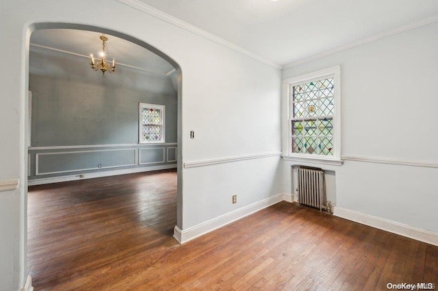 empty room with dark hardwood / wood-style floors, radiator heating unit, crown molding, and a chandelier