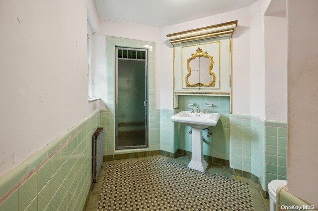 29-37 168th St, Flushing, NY 11358 - bathroom with tile walls, radiator heating unit, wainscoting, toilet, and tile patterned flooring
