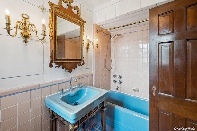 bathroom with sink, tile walls, and tiled shower / bath