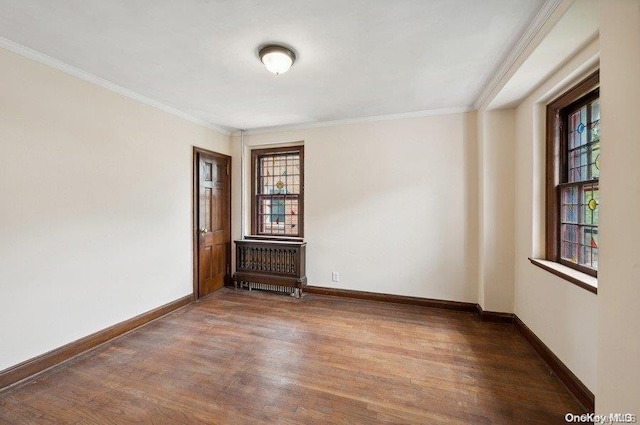 empty room featuring hardwood / wood-style floors, radiator heating unit, crown molding, and a healthy amount of sunlight