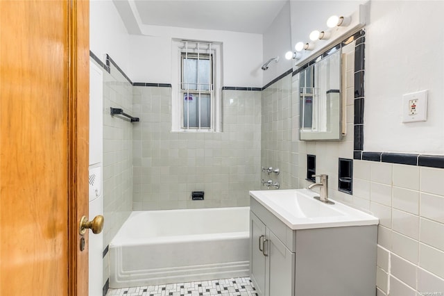 bathroom featuring tile patterned floors, vanity, tiled shower / bath combo, and tile walls