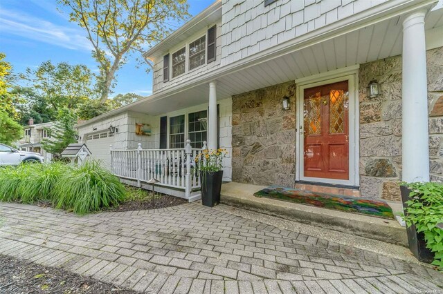 doorway to property with covered porch and a garage