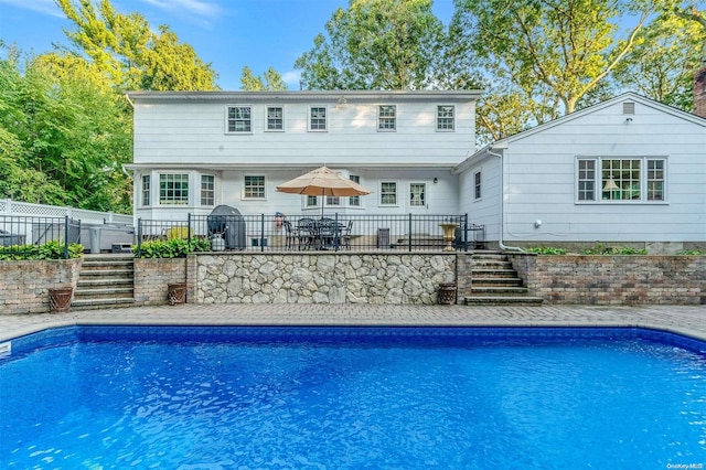 back of property with a fenced in pool