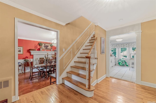 stairs with radiator, an inviting chandelier, ornamental molding, and hardwood / wood-style flooring